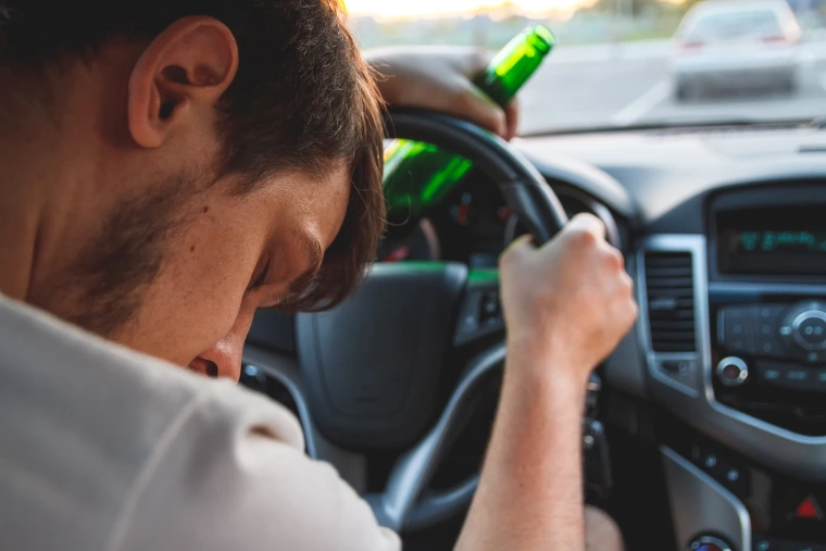 Man passed out behind the wheel of a vehicle with a beer bottle in his left hand